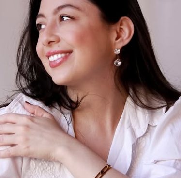 Mulher sorrindo com brincos de cristal e pulseira dourada